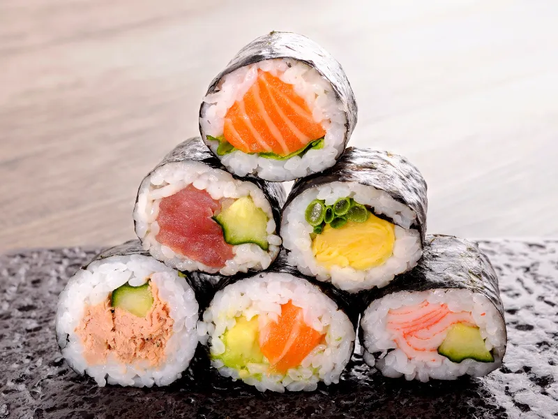 Stacked assorted maki rolls with salmon, tuna, egg and crab fillings